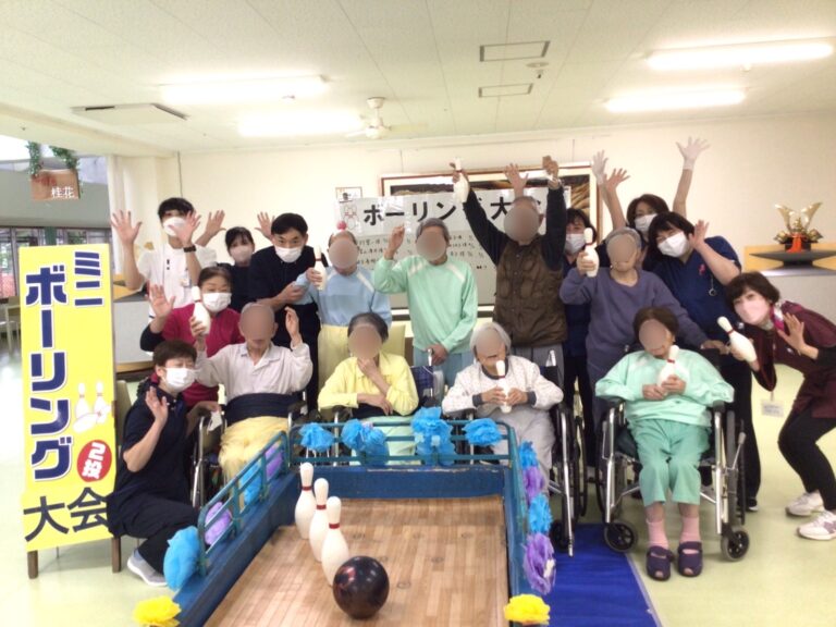 施設の入居者とスタッフがボーリング大会で楽しむレクリエーション風景。車椅子利用者も参加している。